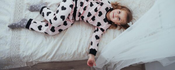 Child in soft warm pajama playing in bed