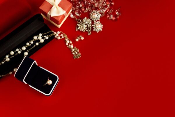 luxury ring and stylish necklace and gift box on red background